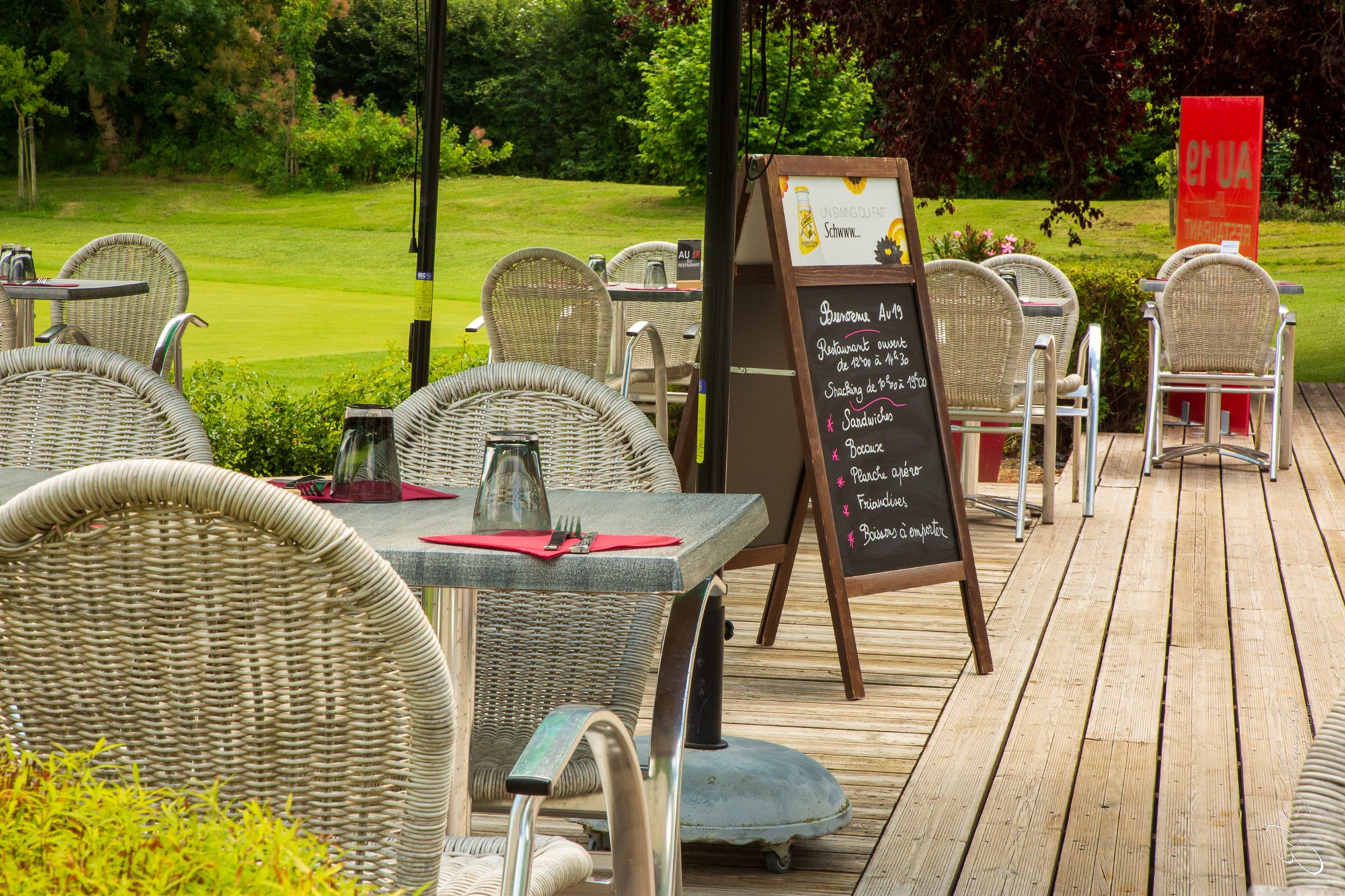 La terrasse du Au19 : tables dressées, fauteuils en osier et l’ardoise du jour, avec le parcours du golf de Niort juste derrière