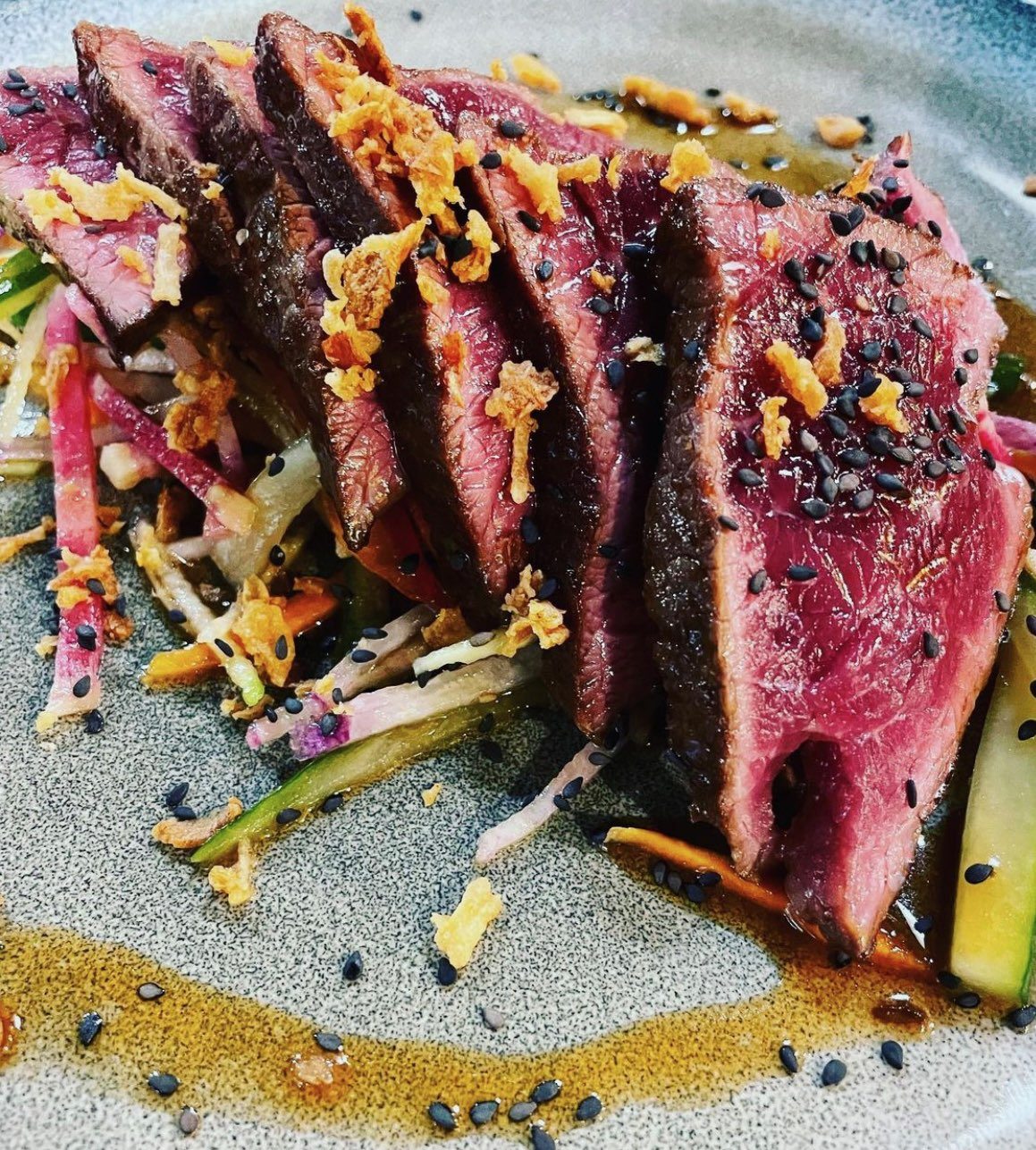 Bœuf juste saisi, tranché, sésame noir et oignons frits sur une julienne de légumes croquants