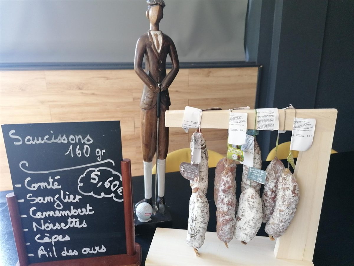 Au comptoir, des saucissons suspendus et leur ardoise : comté, sanglier, noisettes, cèpes