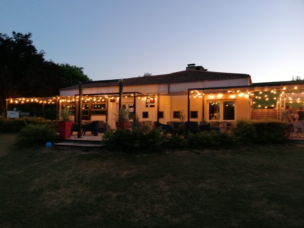 Le Au19 à la tombée du jour, la terrasse éclairée de guirlandes au bord du green