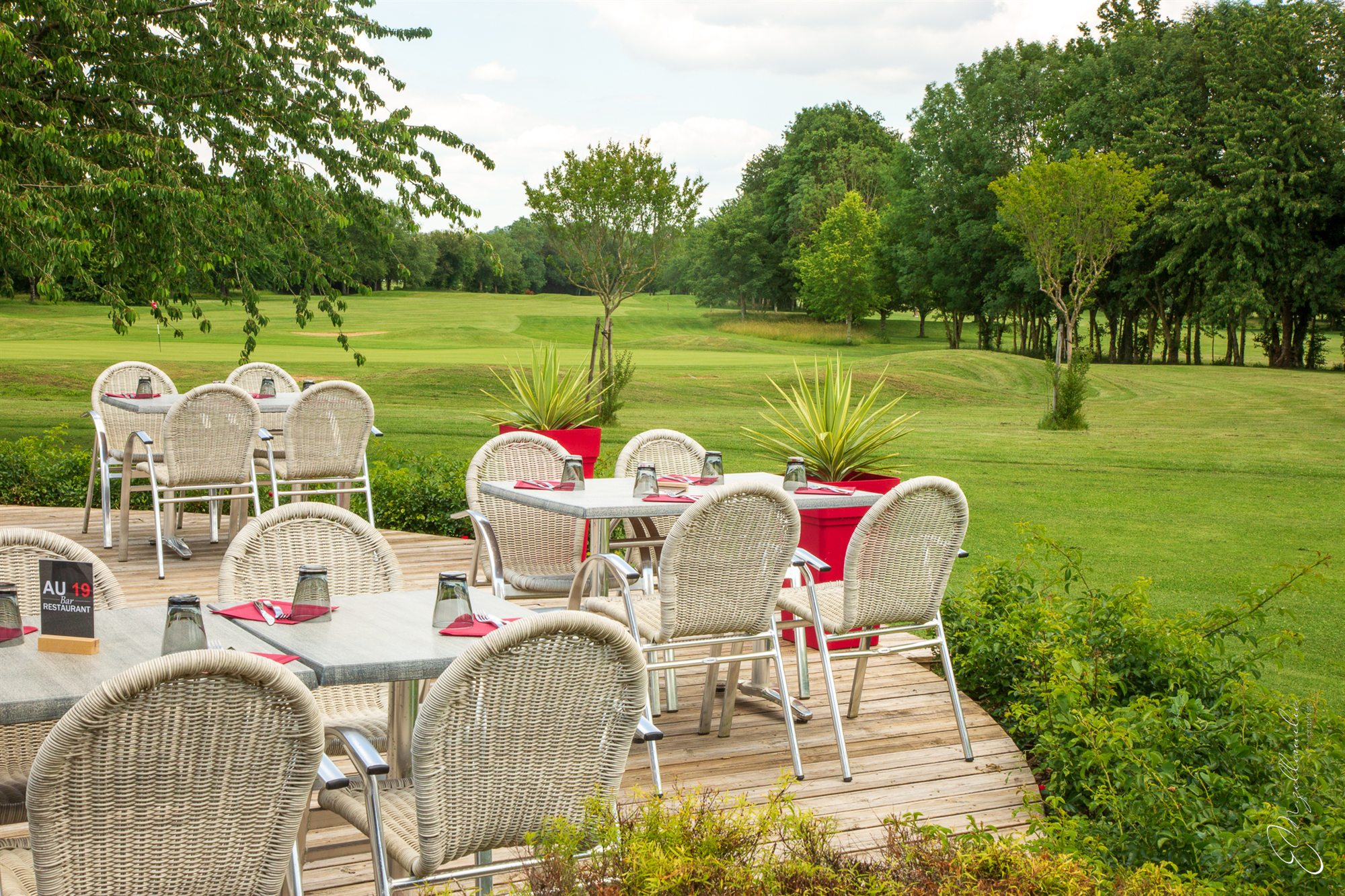 Depuis la terrasse en bois du Au19, la vue file sur le fairway bordé de grands arbres